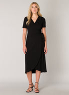Women's black wrap midi dress with a V-neckline, short sleeves, and self-tie waist detail. The soft stretch fabric drapes elegantly through the skirt, creating a flattering silhouette. Shown styled with strappy heeled sandals.