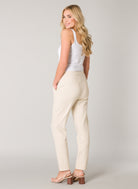 Model wearing women's tapered ankle pants with cuffed hems and welt back pockets, back view