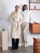 2 Women standing against wall wearing neutral tones