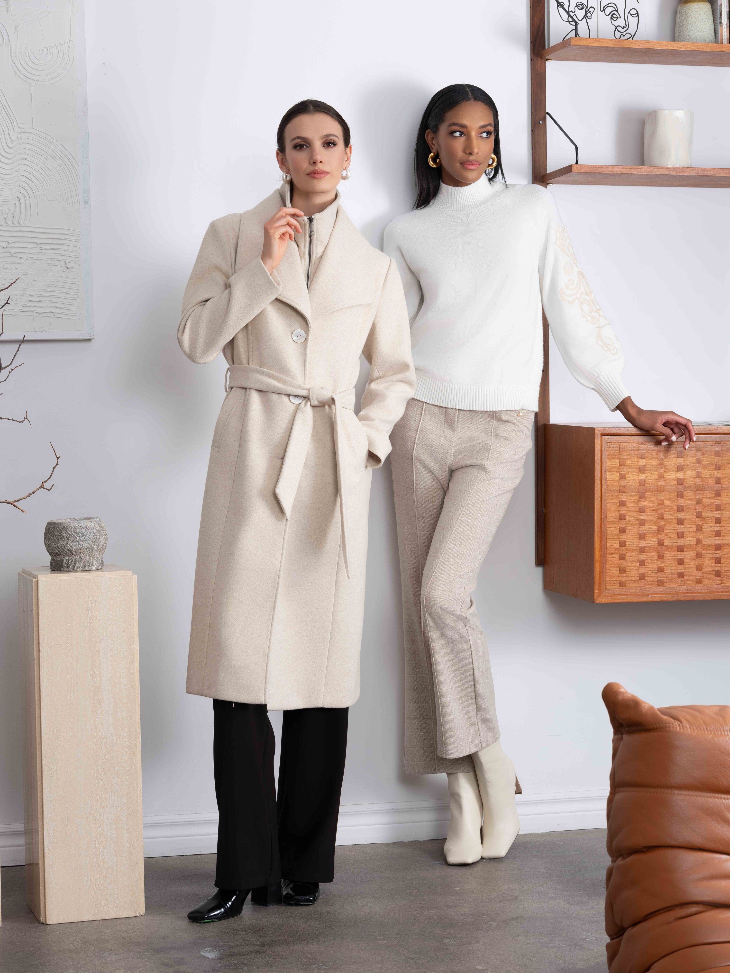 2 Women standing against wall wearing neutral tones