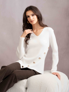 Woman wearing a white sweater with gold buttons on a gray background