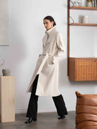 Woman wearing a beige trench coat in a modern interior setting