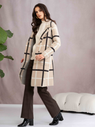 Woman wearing a plaid coat standing against a plain background
