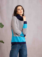 Woman wearing a gray sweater with blue accents against a plain background