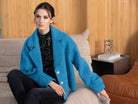 Woman sat on a sofa wearing a teal jacket