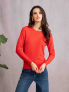 Woman standing wearing orange sweater and denim jeans