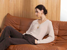 Woman sitting on a brown leather couch with a wooden wall background