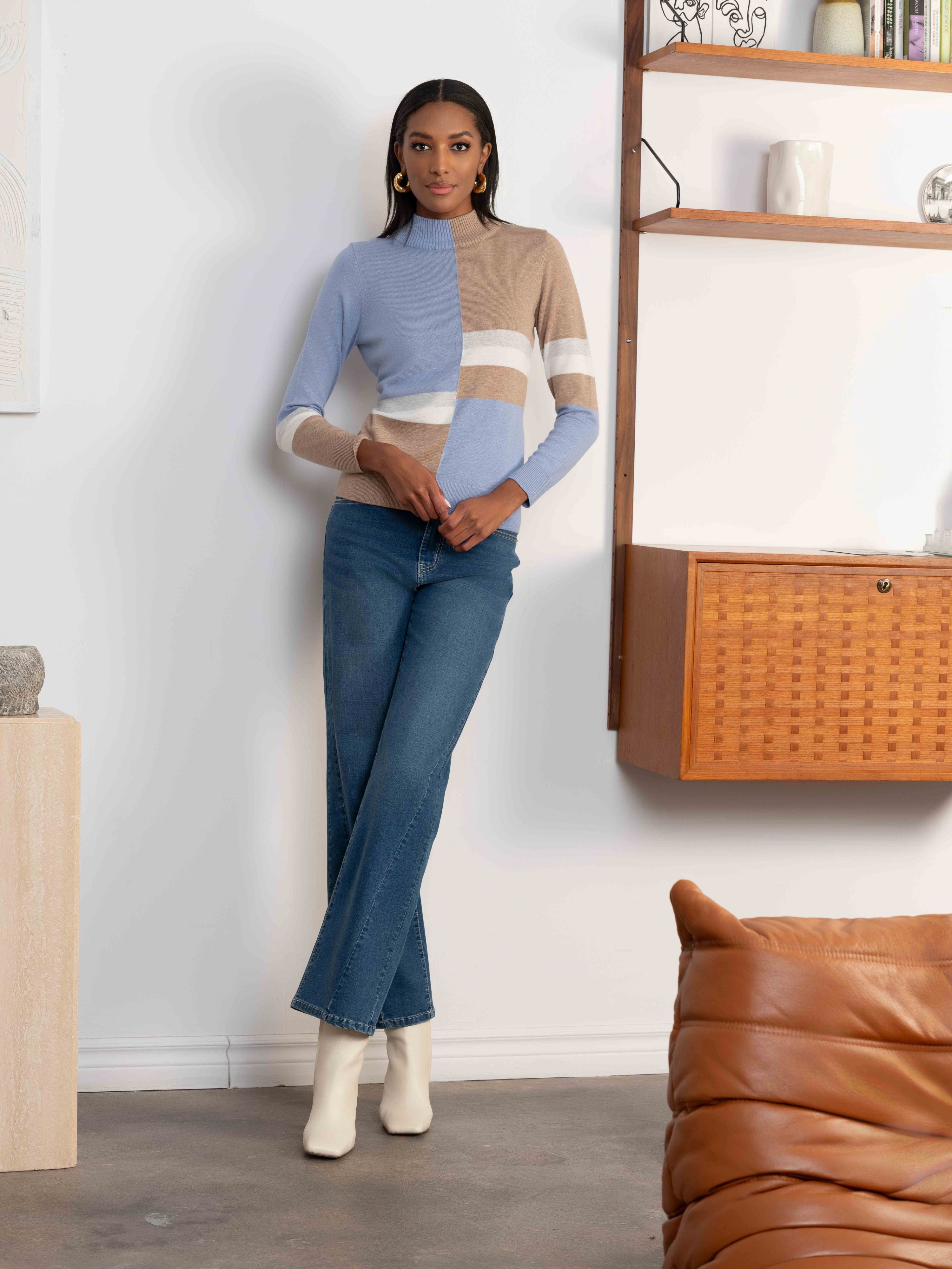 Woman wearing a color-blocked sweater and jeans in a modern living room.