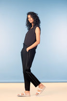 Woman wearing a black sleeveless top and black pants against a blue background