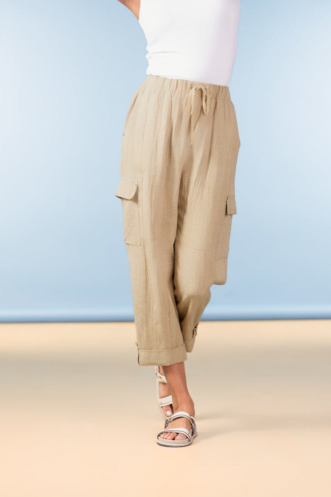 Person wearing beige cargo pants on a beach with a blue sky background