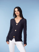 Close-up view of textured knit cardigan featuring a button-front design and soft drape, styled with relaxed-fit pants.