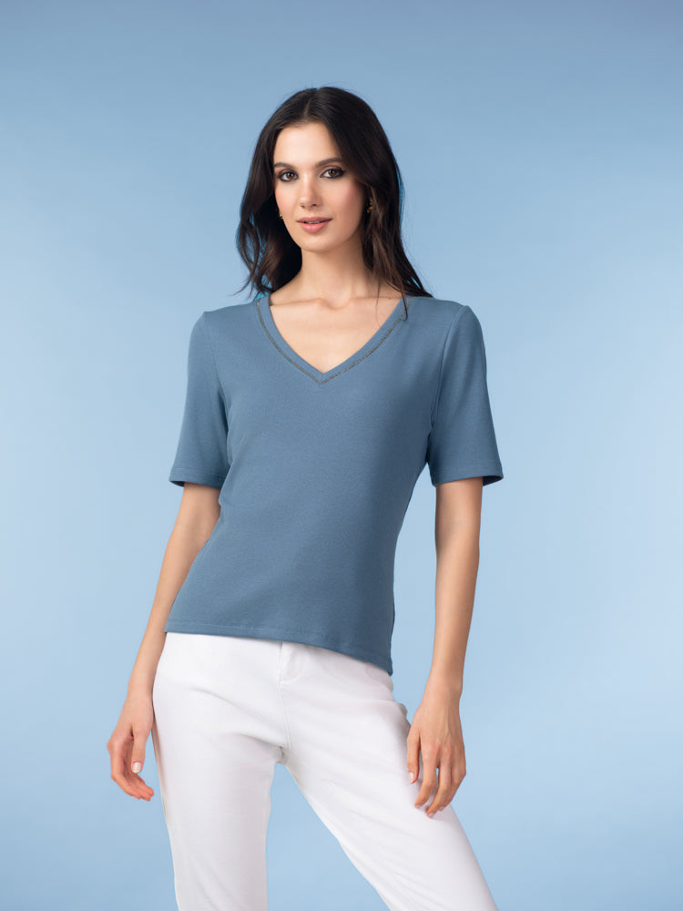 Model wearing a women’s short-sleeve V-neck knit top featuring a smooth, softly draped silhouette, styled with a polished, everyday look.