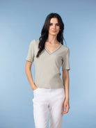 Model wearing a women’s short-sleeve V-neck knit top featuring a smooth, softly draped silhouette, styled with a polished, everyday look.