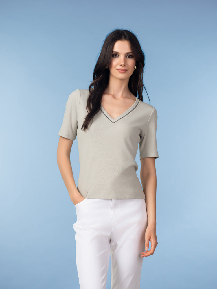 Model wearing a women’s short-sleeve V-neck knit top featuring a smooth, softly draped silhouette, styled with a polished, everyday look.
