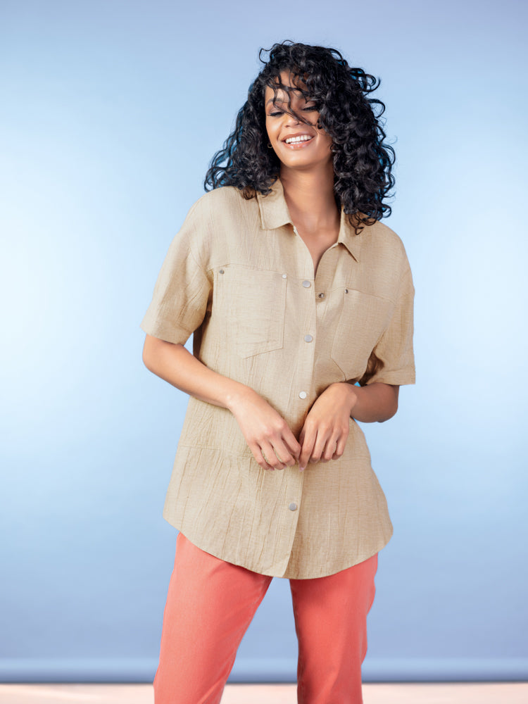 Women’s relaxed short-sleeve button-up blouse in a lightweight viscose-linen blend, featuring a collared neckline, front button closure, and easy drape, styled with casual trousers.