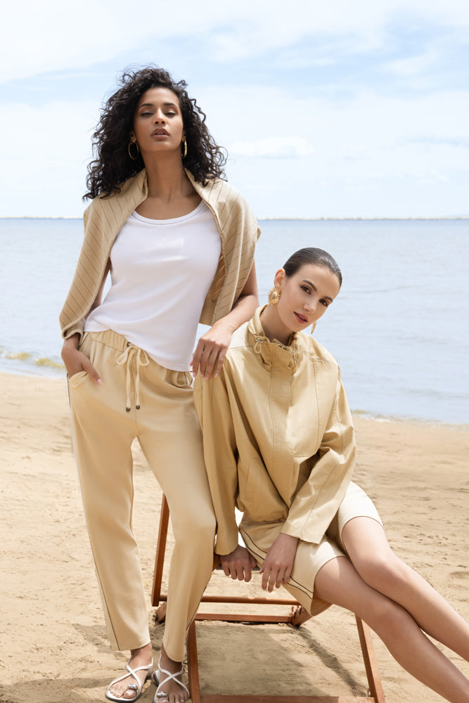 Women’s short-sleeve knit t-shirt styled casually, shown in a relaxed outdoor setting with another person close by sitting down on a chair. 