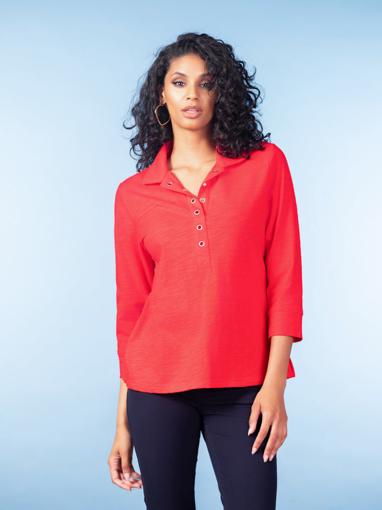 Model wearing a red cotton henley blouse with three-quarter sleeves and button-front neckline, paired with black pants against a light blue studio background.
