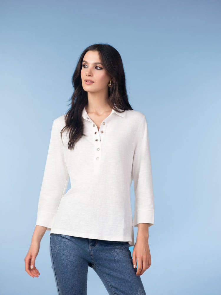 Model wearing a white cotton henley blouse with three-quarter sleeves and button-front neckline, styled with blue jeans against a light blue studio background.
