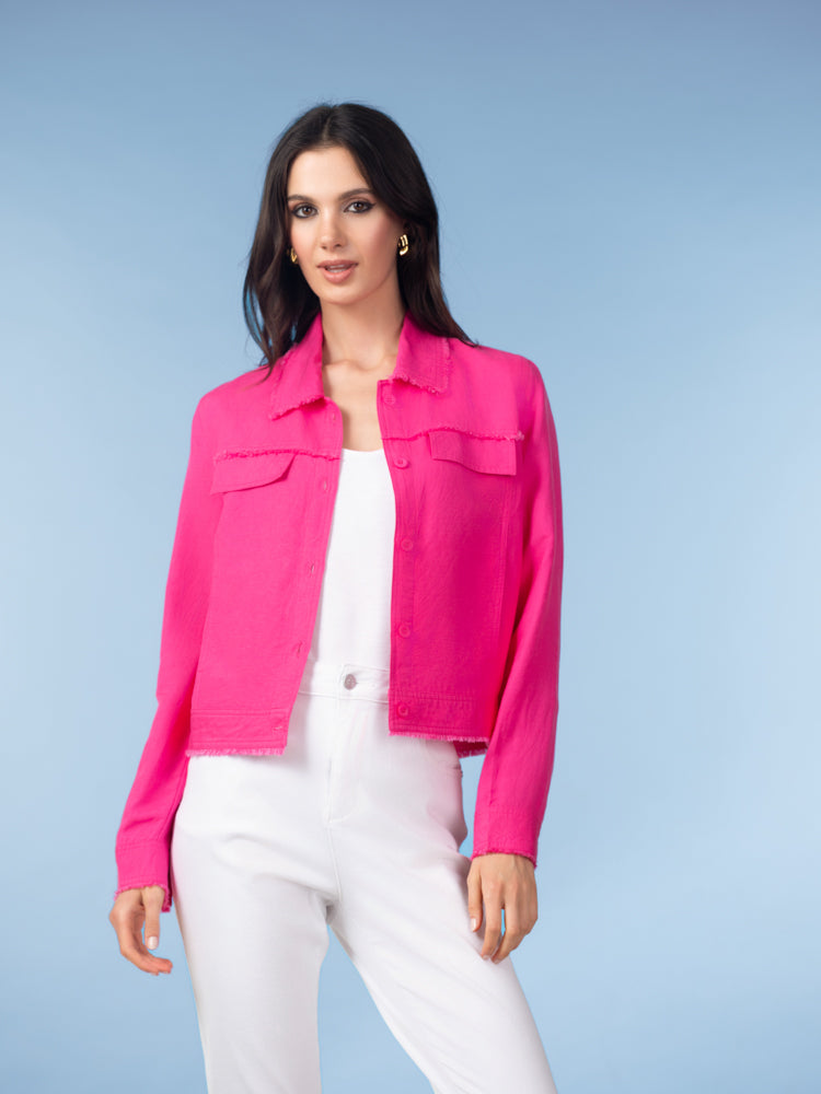 Woman wearing a bright pink cropped linen blend jacket with front pockets and button closure, paired with white trousers against a soft blue studio background.
