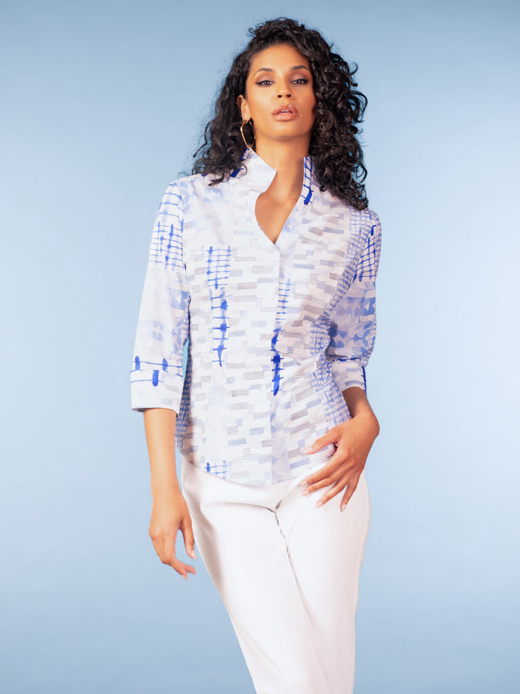 Model wearing a light blue and white patterned cotton blouse with a stand collar and three-quarter sleeves, paired with white pants against a studio background.