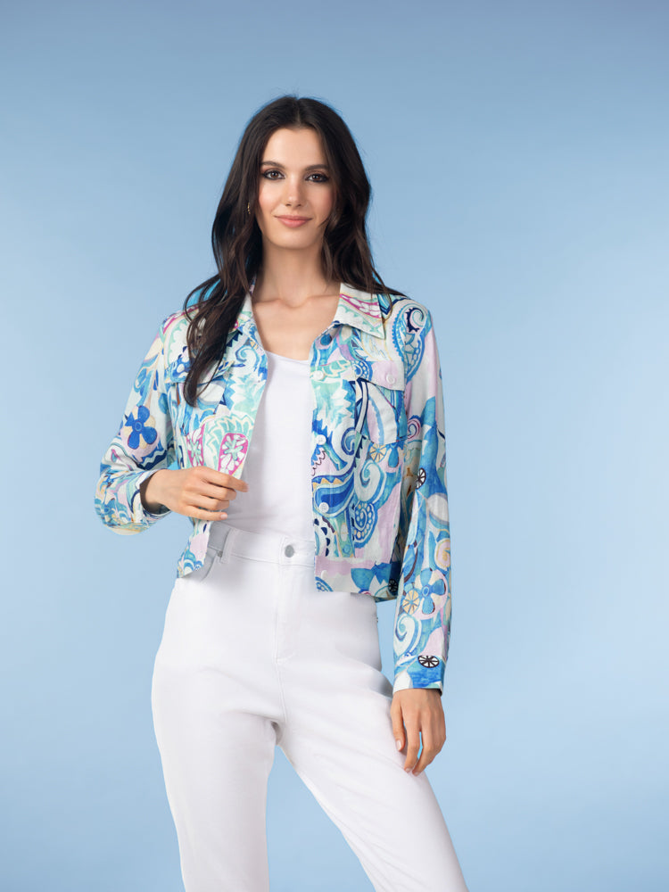 Woman modelling a cropped printed linen-blend jacket in soft blue and aqua tones with a button-front closure, styled over a white top and high-waisted light grey trousers against a studio background.