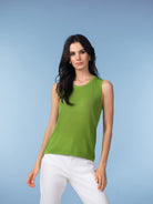 Women’s green sleeveless knit tank top with round neckline, paired with white pants.