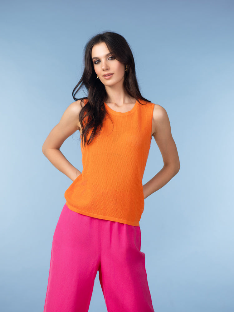 Women’s bright orange sleeveless knit tank top with round neckline, styled with pink wide-leg pants.