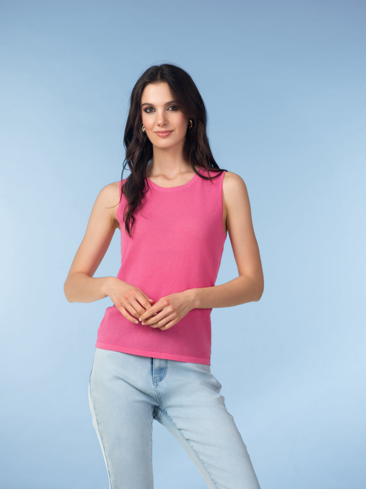 Women’s pink sleeveless knit tank top with round neckline, paired with light blue jeans.