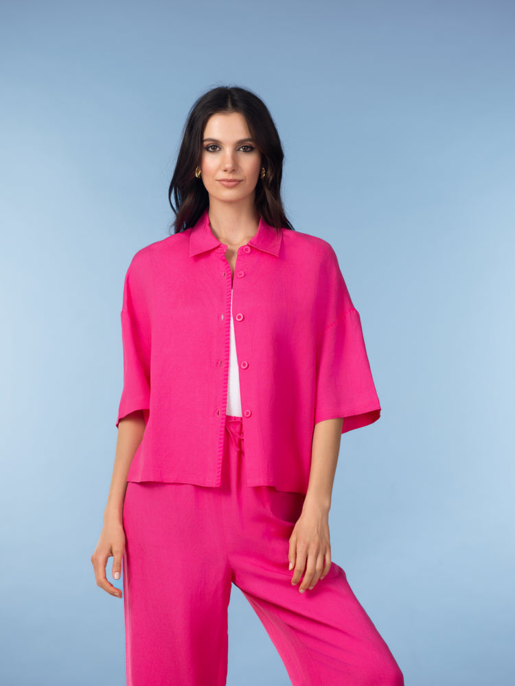Front view of a vibrant pink linen blend short-sleeve button-up shirt with wide-leg pants, showing the relaxed drape and soft structure.