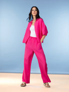 Model wearing a bright pink relaxed-fit linen blend shirt layered over a tank top with coordinating wide-leg pants and sandals.