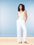 Wide-Leg Pant in white, styled with a beige sleeveless tank and neutral flat sandals against a soft blue studio backdrop.