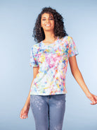 Woman wearing an abstract print short-sleeve crewneck T-shirt with a relaxed fit, paired with slim-fit jeans, shown against a neutral studio background.