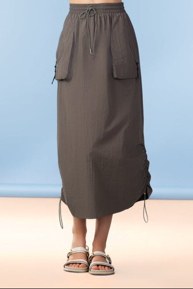 Woman wearing a textured top and brown skirt against a blue background