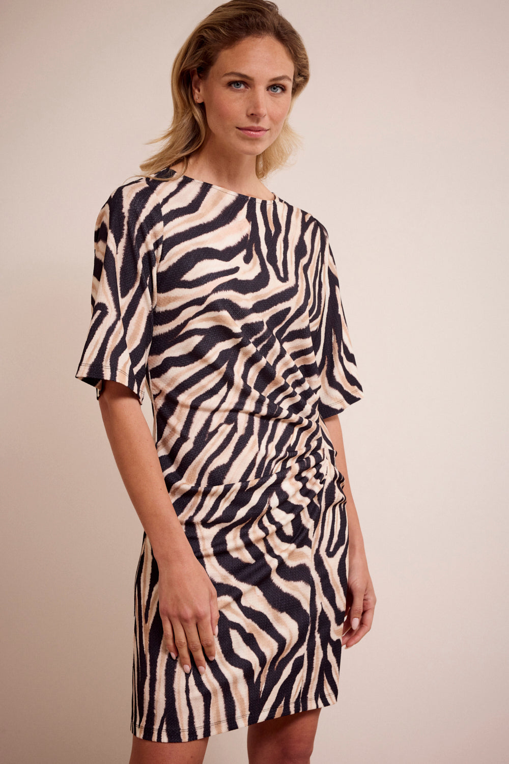 Woman wearing a zebra print dress against a plain background