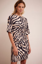 Woman wearing a zebra print dress against a plain background
