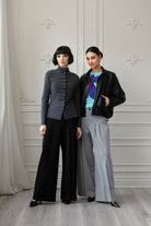 2 Women wearing black and grey pants with a black jacket and grey top