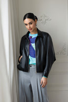 Woman wearing black jacket with blue shirt and grey pants