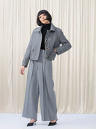 Woman standing in grey jacket with white backdrop
