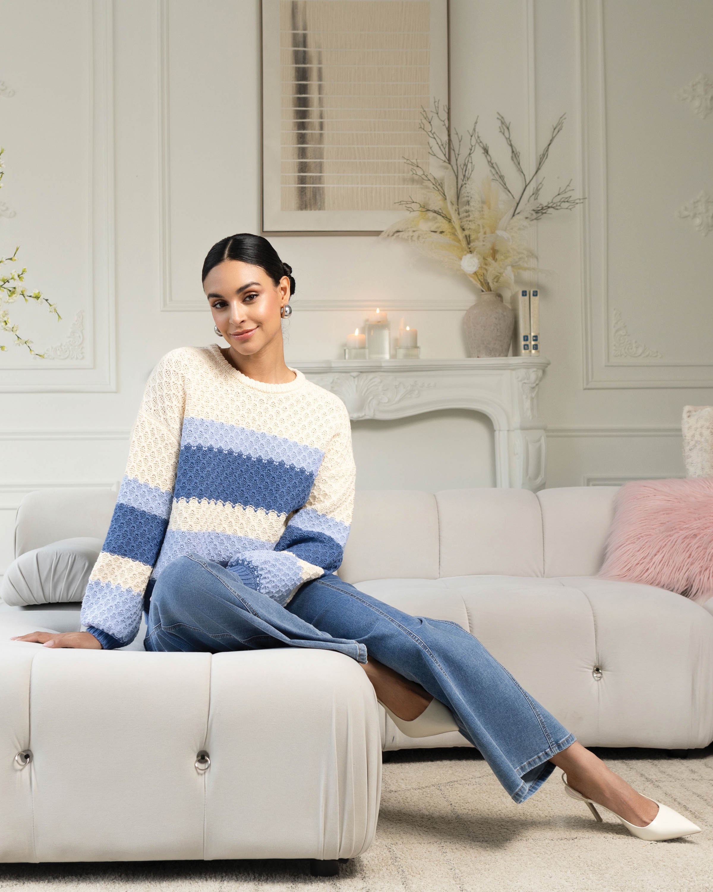 Woman sitting on sofa with cream and blue sweater