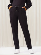 Person wearing black jogger pants with a plain background