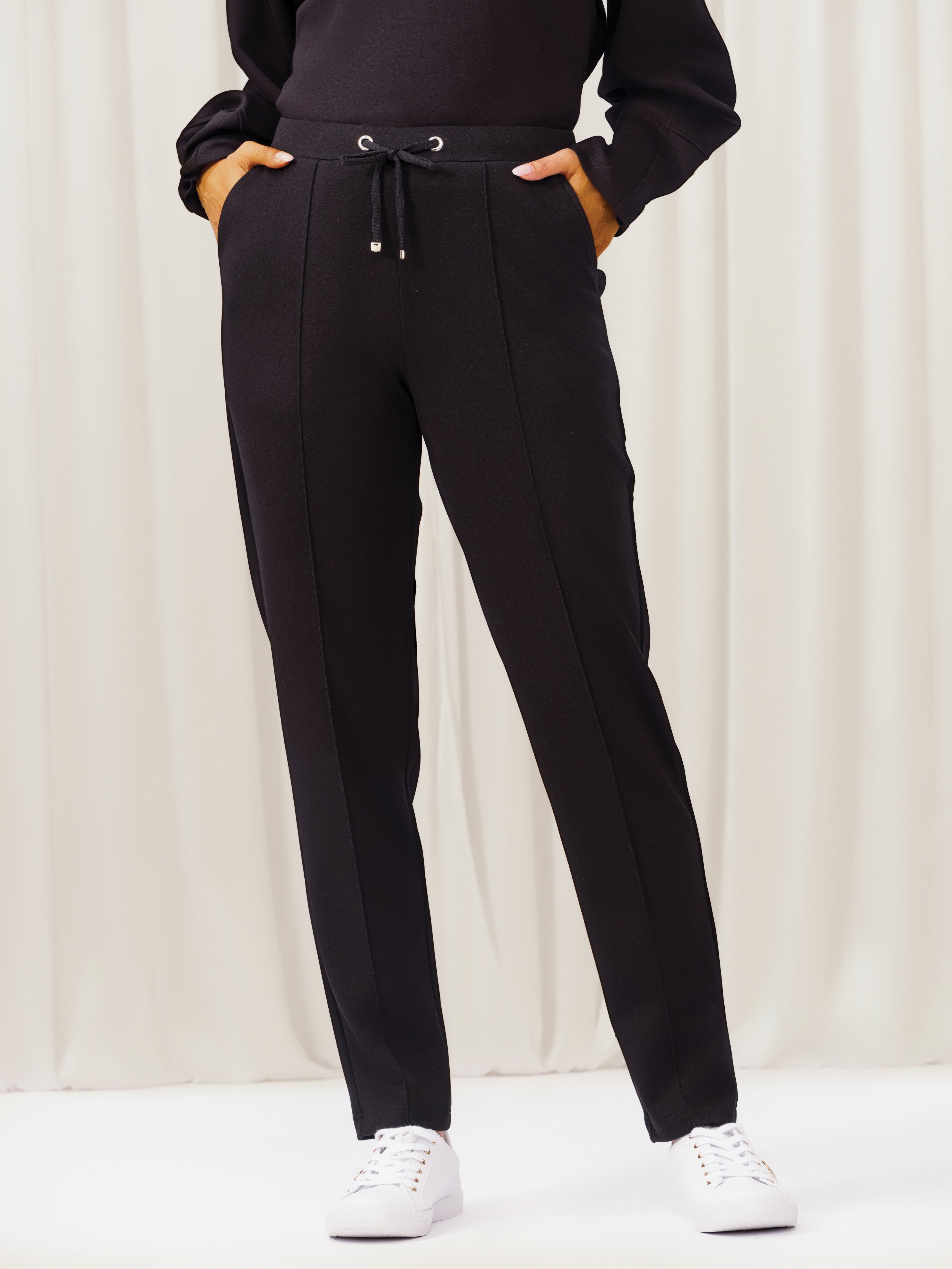 Person wearing black jogger pants with a plain background