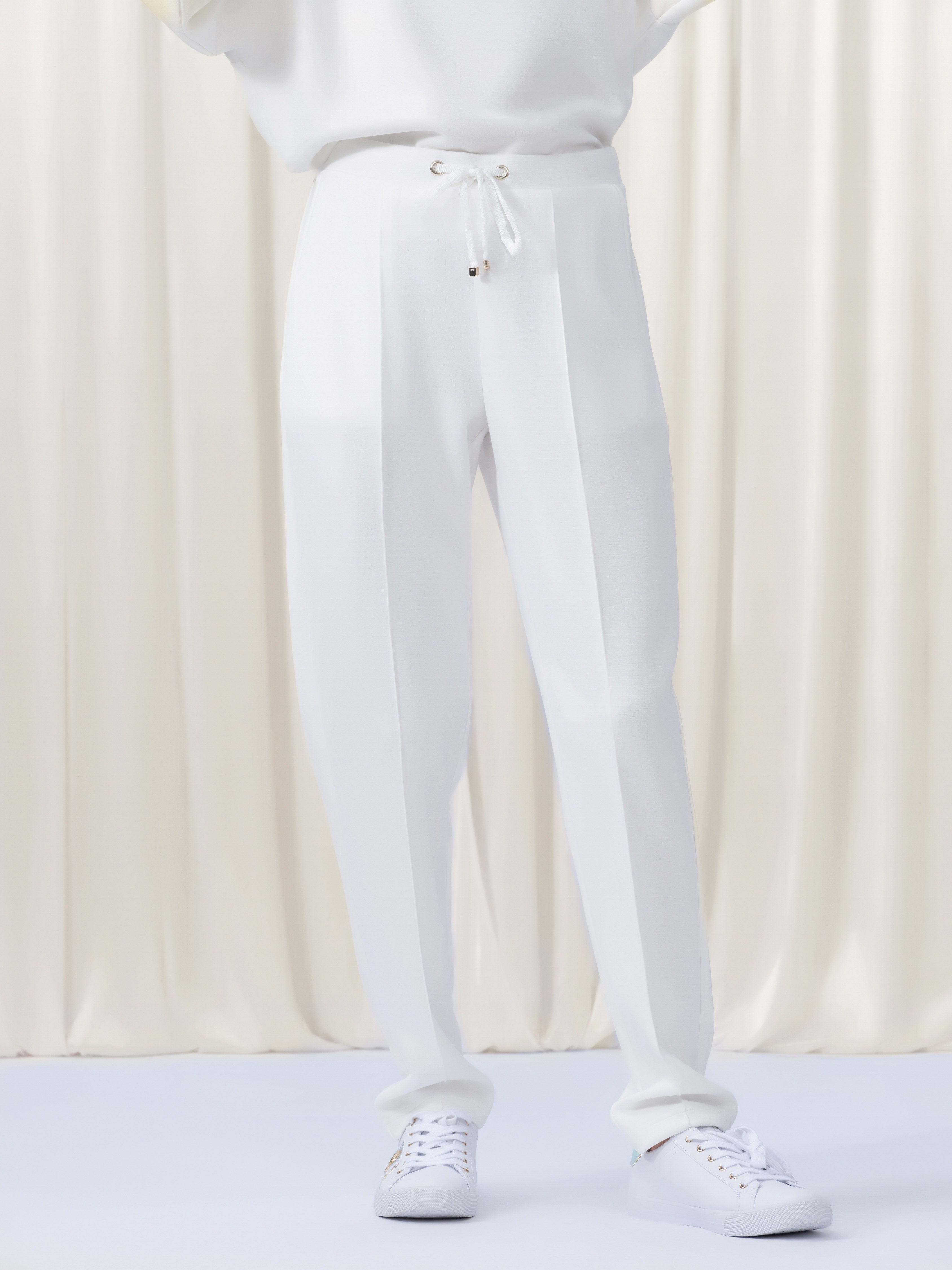 White pants worn by a person on a white background