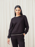 Woman wearing a black sweater and pants against a white background