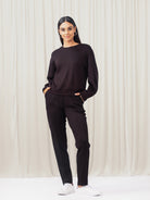 Woman wearing a black outfit against a white curtain background