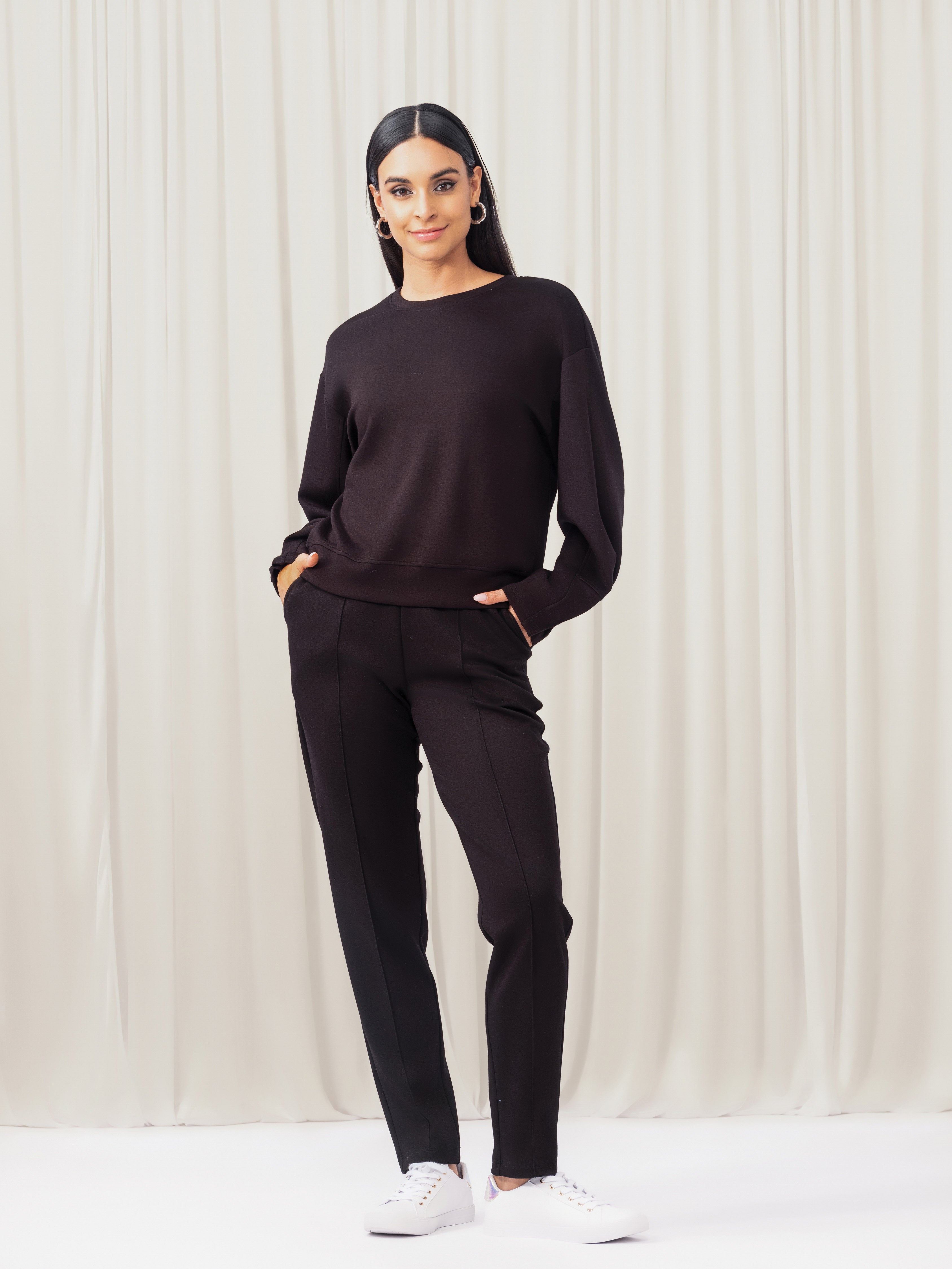 Woman wearing a black outfit against a white curtain background