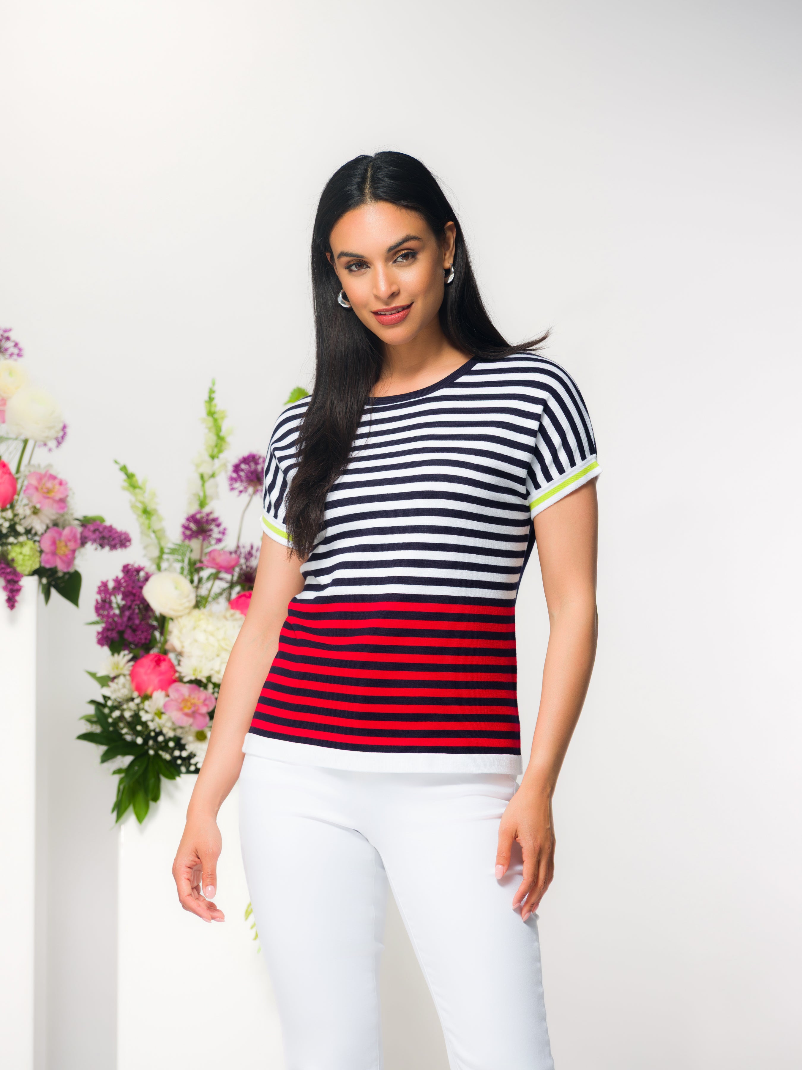 Model wearing a short-sleeve striped knit top with a crew neckline and a relaxed, flattering fit, styled with fitted pants in a studio setting.
