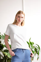 Women’s ivory short-sleeve crew neck t-shirt with side accent detail, paired with light blue denim jogger-style jeans.