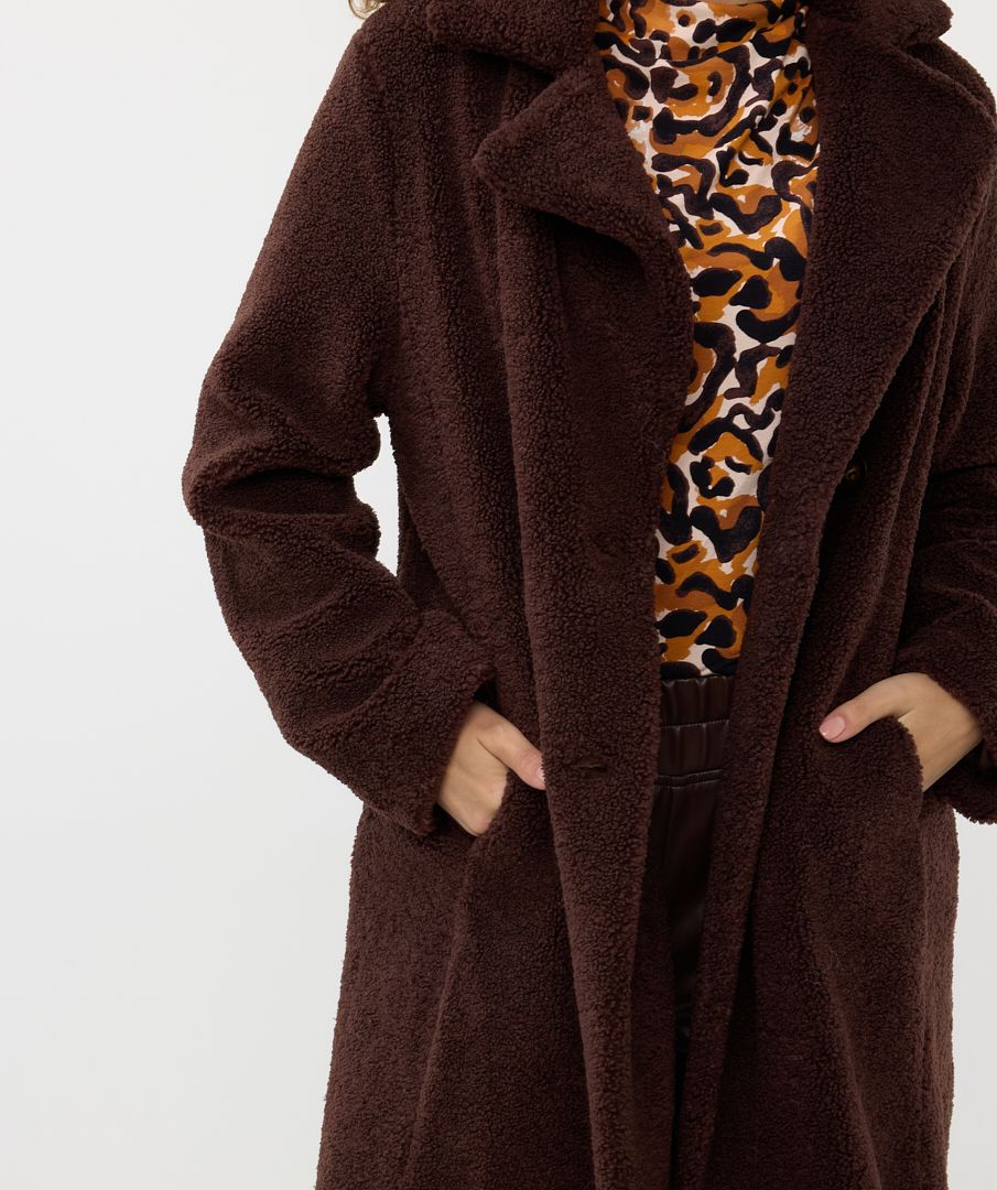 Woman wearing brown coat with leopard print top on a white background
