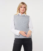 Woman wearing a textured sleeveless sweater vest layered over a collared shirt