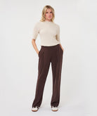 Woman modelling an ivory ribbed knit short-sleeve top with a high neckline and fitted silhouette, shown from the front.